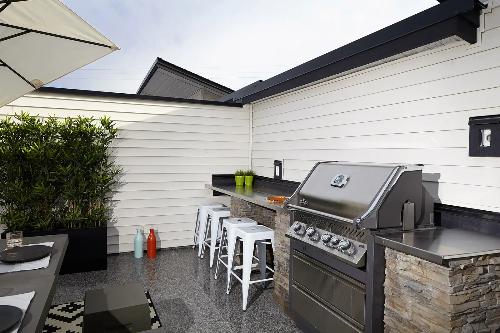 A backyard scene featuring a grill and a table with chairs on vinyl decking, perfect for outdoor dining and gatherings.