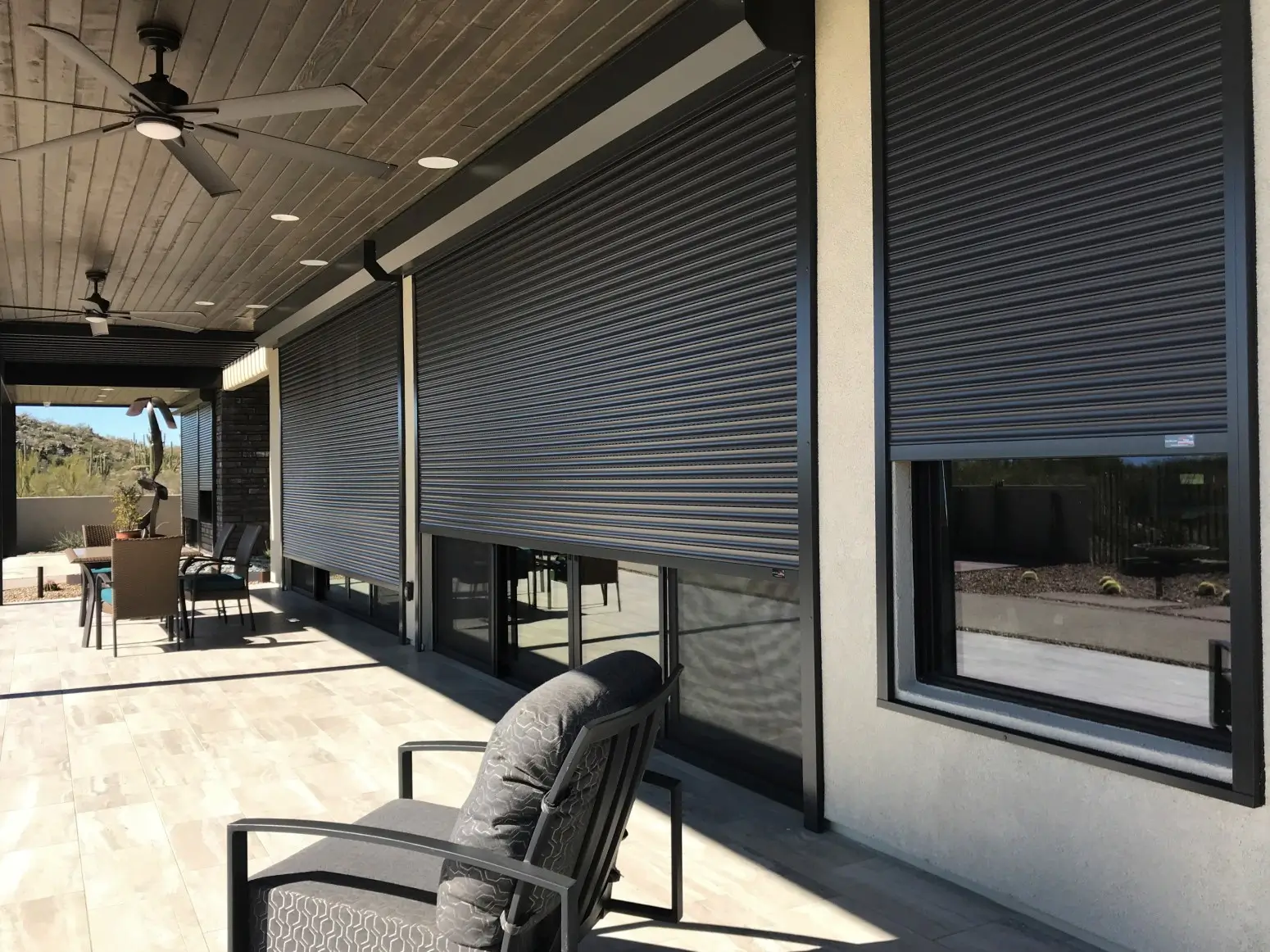 A patio scene showcasing a large sliding door, several chairs, and Roll Shutters for weather protection.