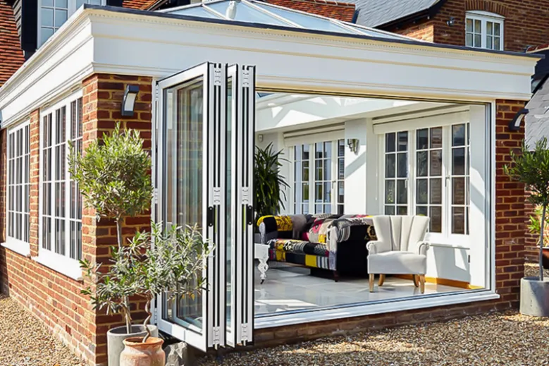 A white patio featuring WeatherMaster™ Bi-Fold Doors, with stylish patio furniture arranged for outdoor relaxation.