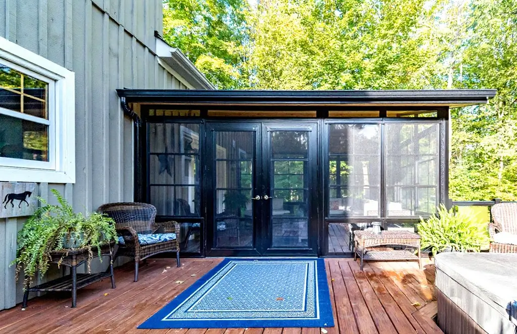 A screened porch featuring a patio table and chairs, equipped with WeatherMaster™ Doors for enhanced outdoor comfort.