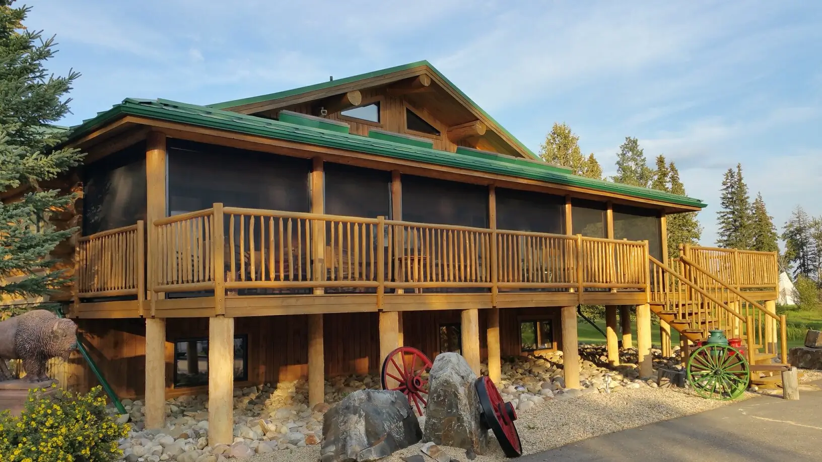 A sizable wooden house with an expansive deck and a large rock nearby, equipped with a Retractable Screen for convenience.
