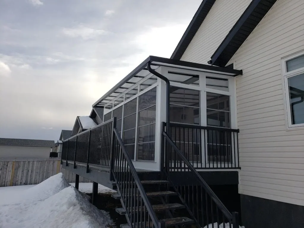 A porch with stairs leading to a house, featuring a sturdy railing system for safety and support.