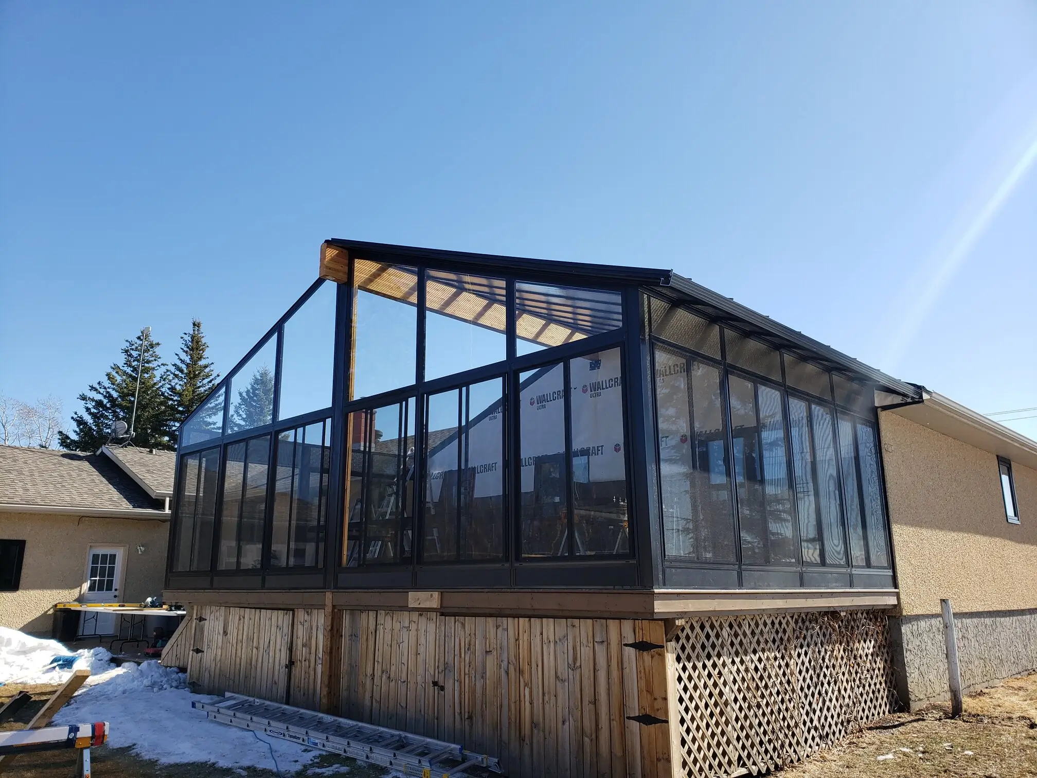 A cozy glass enclosed Sunroom with a wooden deck, perfect for enjoying the outdoors in any season.