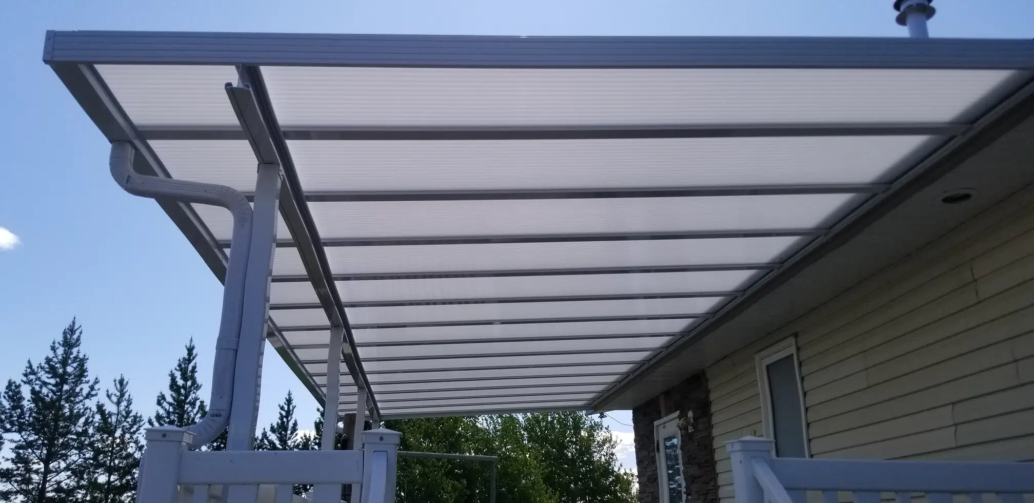 A white awning on a house, complemented by a white fence, showcasing an Acrylic Patio Cover design.