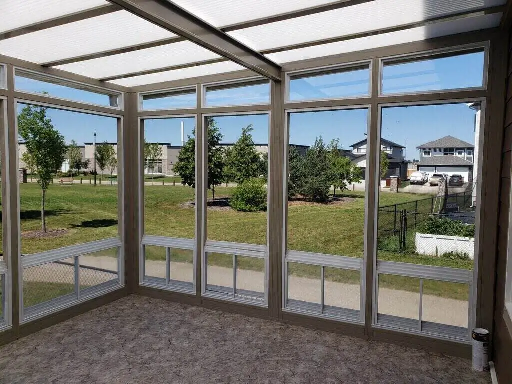 A bright 3-Season Sunroom featuring a large glass window and a cozy patio area for relaxation.
