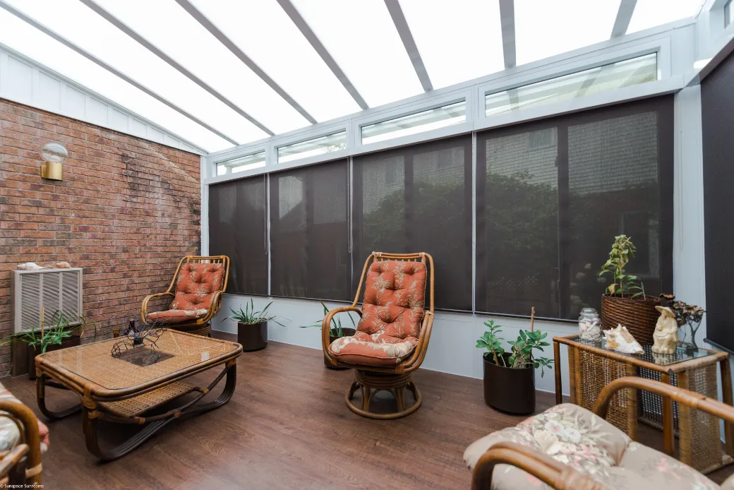 A bright sunroom featuring comfortable chairs and a table, perfect for relaxing or enjoying meals.