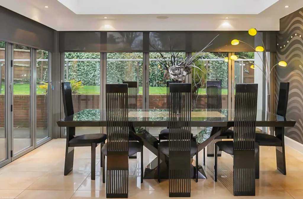 Contemporary dining room with a glass table and chairs, complemented by Bi-Fold Doors for natural light.