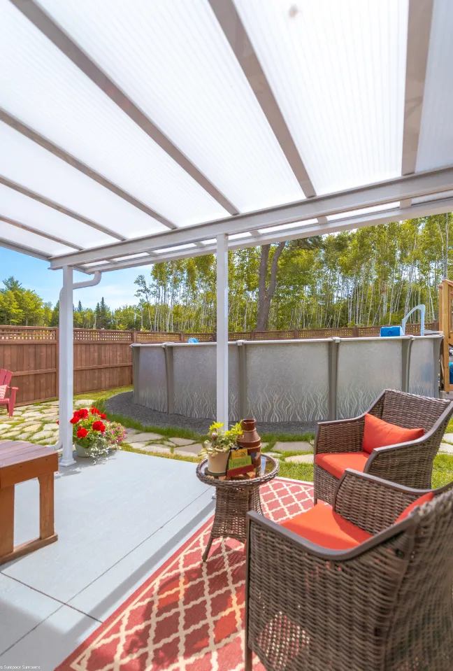 A cozy patio with wicker seating arranged beneath a protective acrylic cover, ideal for outdoor relaxation.