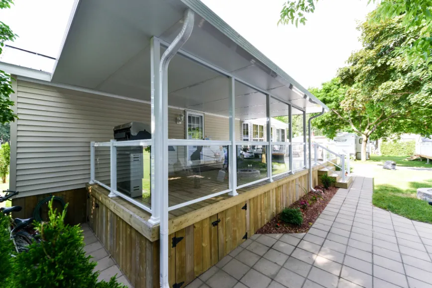 A covered deck on a patio with a table, surrounded by aluminum railing and glass for a modern look.