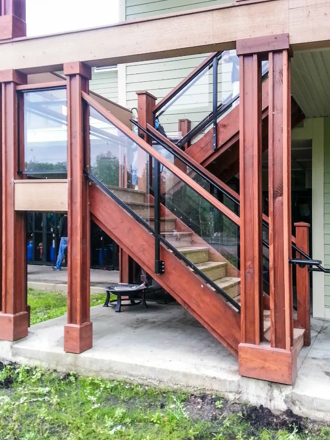 A wooden staircase complemented by elegant glass railings, highlighting a contemporary aesthetic with aluminum details.
