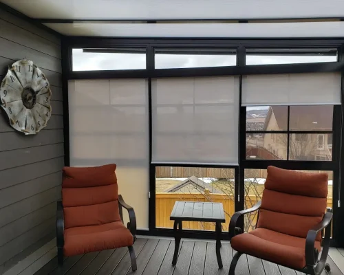 A deck features two chairs and Roll Shutters, providing a view of the bustling city below.